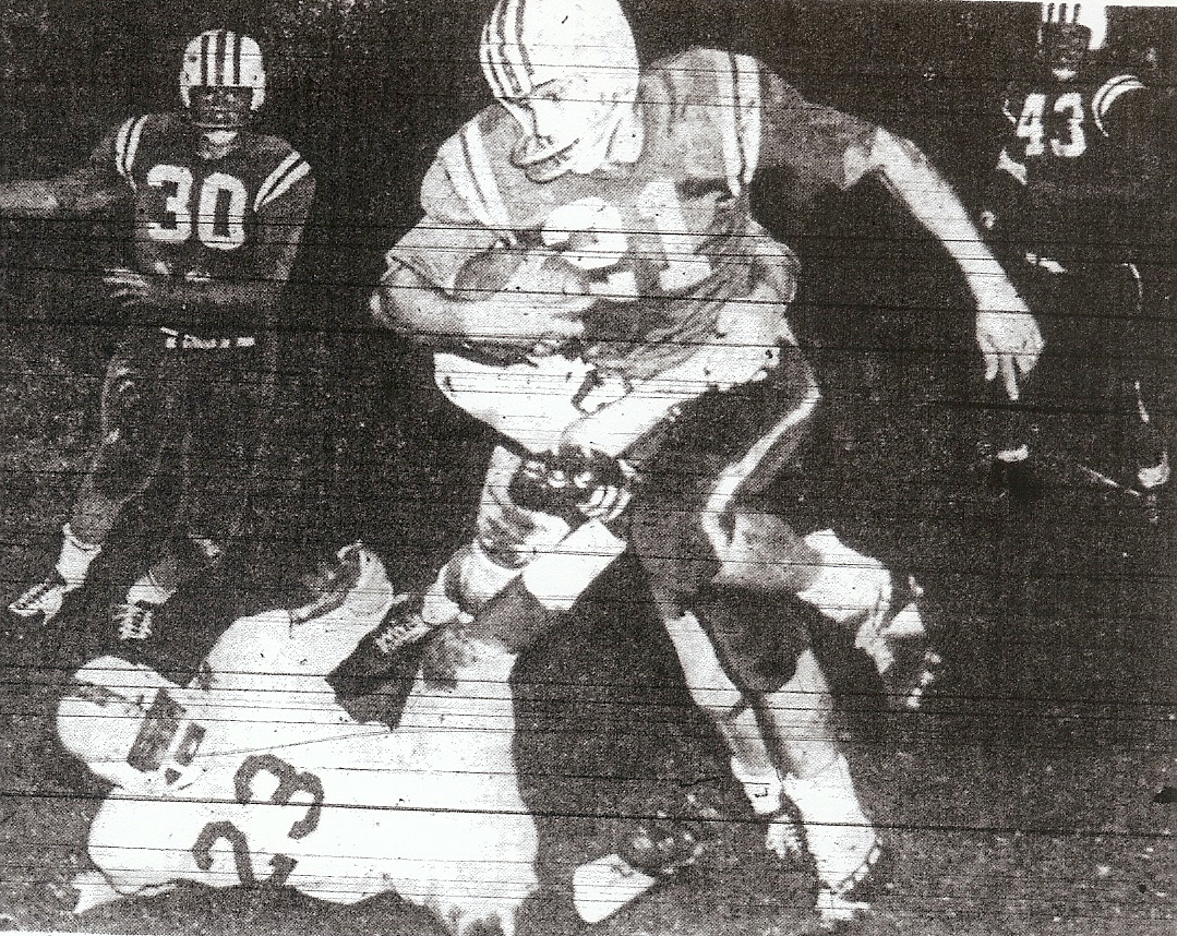 Crawford's Bill Rainey, all Southern California, is tackled by unidentified Kearny defender, while Don Henderrson (23), Jimmy Gilbert (30), and Larry Guske (43) are witnesses. Colts won San Diego Section title.