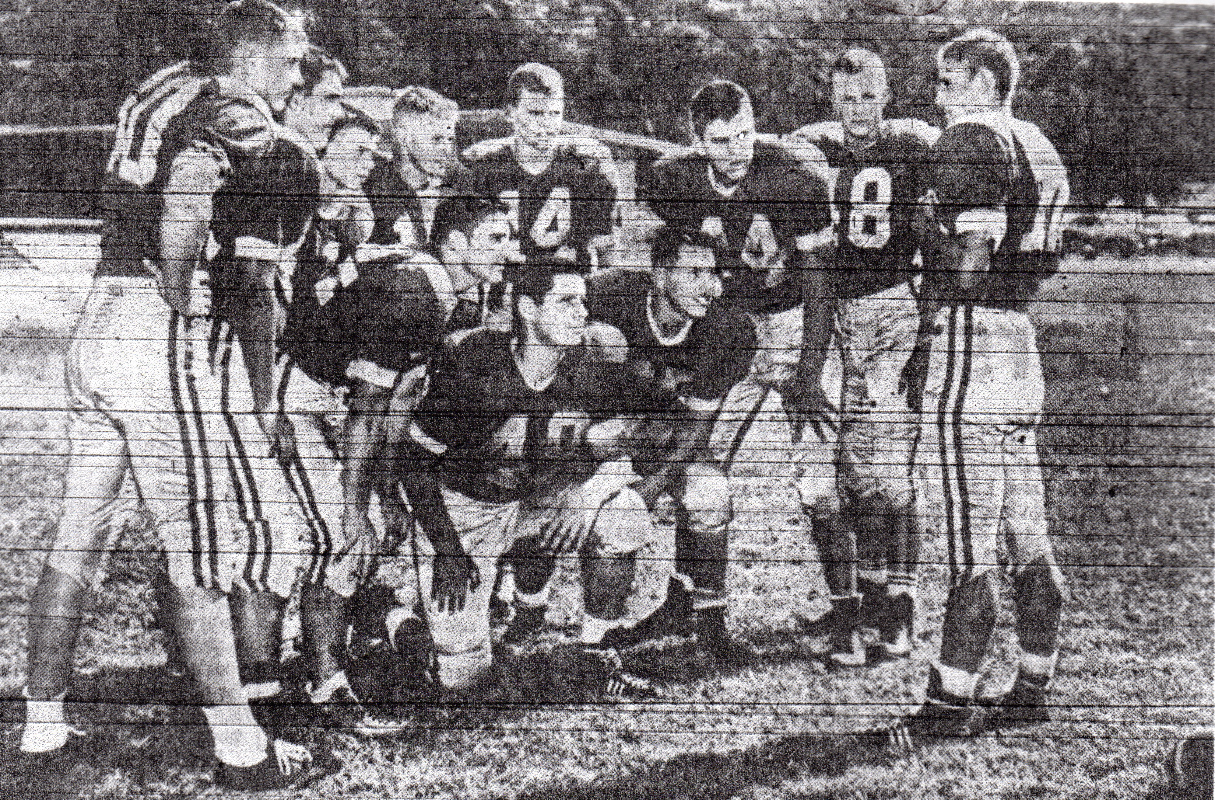 The ball is almost obscured at lower right, but significance of photo is that Grossmont quarterback Dick Cooksey huddled his team that close to the pigskin with visual signal system that involved picking colored peg from Cooksey's belt. Cooksey and Grossmont Foothillers unveiled new huddle formation at Metropolitan League carnival.